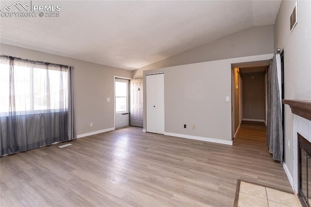 138 Hoedown Cir, Fountain, CO 80817 - unfurnished living room with light wood-style flooring, a fireplace, lofted ceiling, and visible vents