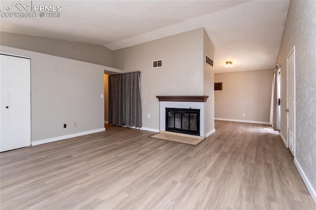 138 Hoedown Cir, Fountain, CO 80817 - unfurnished living room with a fireplace with flush hearth, vaulted ceiling, visible vents, light wood finished floors, and baseboards