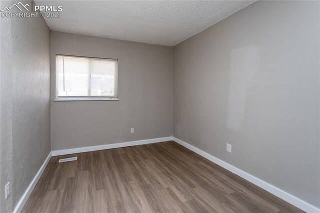 138 Hoedown Cir, Fountain, CO 80817 - spare room featuring visible vents, baseboards, a textured ceiling, and wood finished floors
