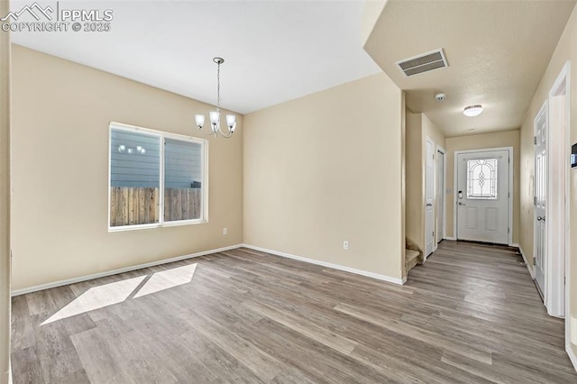interior space featuring baseboards, wood finished floors, a chandelier, and visible vents
