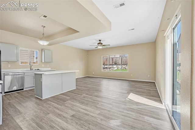 kitchen featuring light wood-style flooring, a sink, visible vents, dishwasher, and light countertops