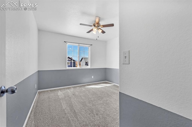 carpeted empty room with a textured wall, a ceiling fan, and baseboards
