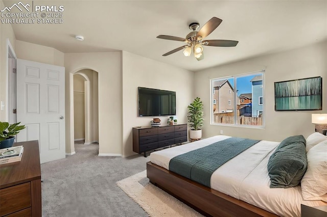 carpeted bedroom with arched walkways, a ceiling fan, and baseboards