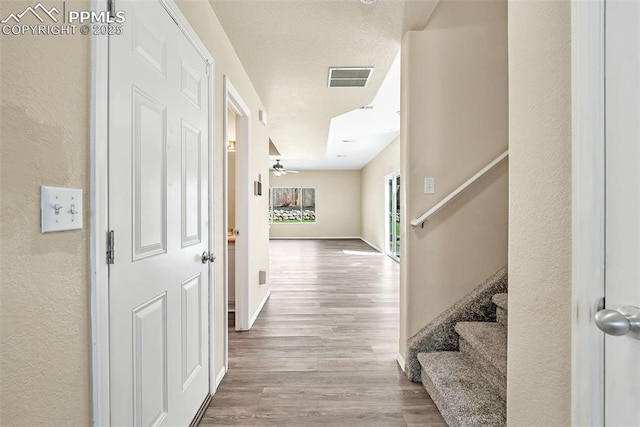 corridor with baseboards, wood finished floors, visible vents, and stairs