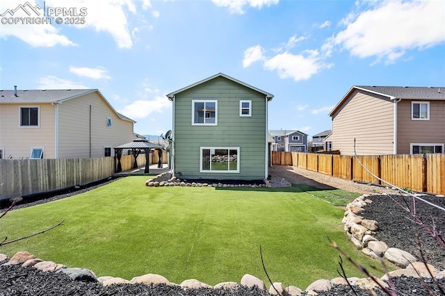 rear view of house with a fenced backyard, a gazebo, and a yard