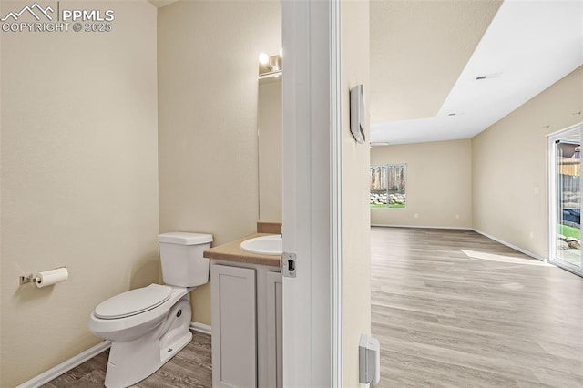 bathroom featuring toilet, vanity, wood finished floors, and baseboards