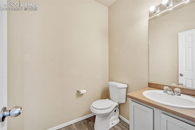 bathroom featuring toilet, vanity, wood finished floors, and baseboards