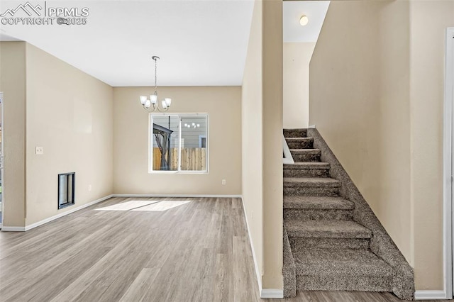 staircase featuring baseboards, wood finished floors, and an inviting chandelier