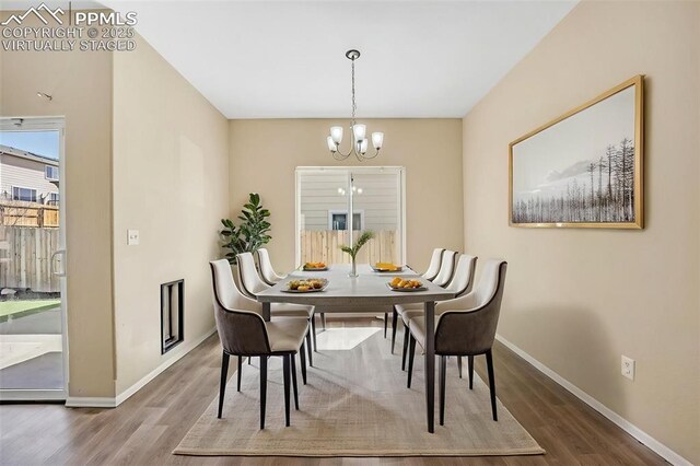 dining space featuring a chandelier, wood finished floors, and baseboards