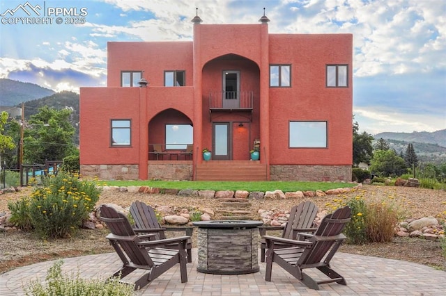 exterior space featuring a patio area, a mountain view, an outdoor fire pit, and stucco siding