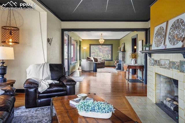 living room with a tile fireplace, baseboards, and wood finished floors