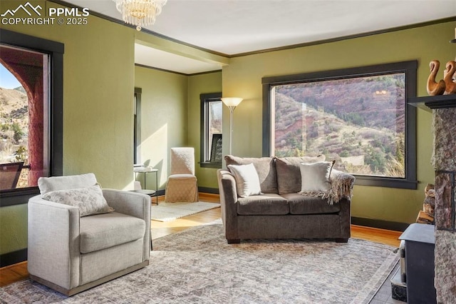 living area featuring a chandelier, baseboards, ornamental molding, and wood finished floors