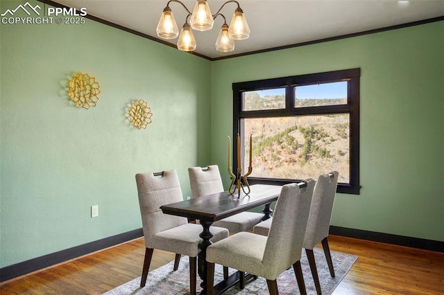 dining area featuring crown molding, baseboards, a chandelier, and wood finished floors