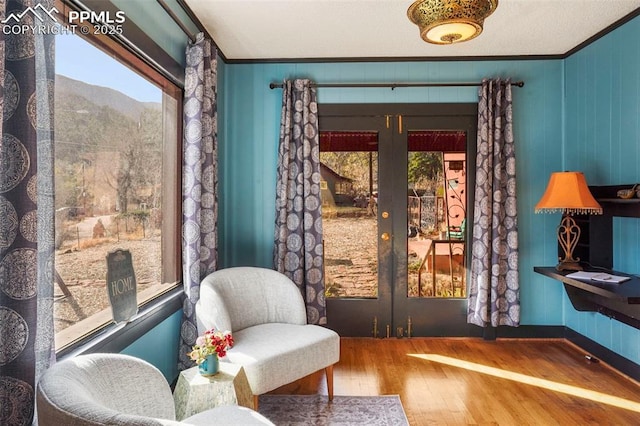 living area with ornamental molding, french doors, wood-type flooring, and a healthy amount of sunlight