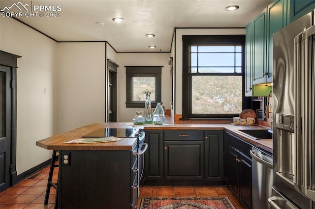 kitchen with dark tile patterned floors, wooden counters, appliances with stainless steel finishes, and recessed lighting