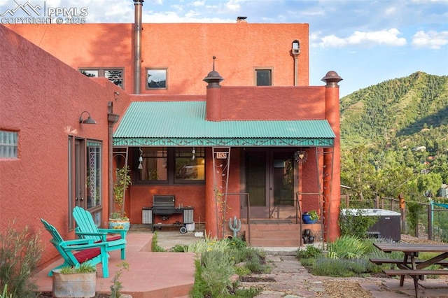 back of house featuring a mountain view, a patio area, stucco siding, and metal roof