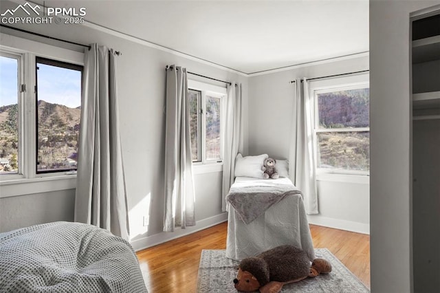 sitting room with light wood-style flooring, ornamental molding, and a healthy amount of sunlight