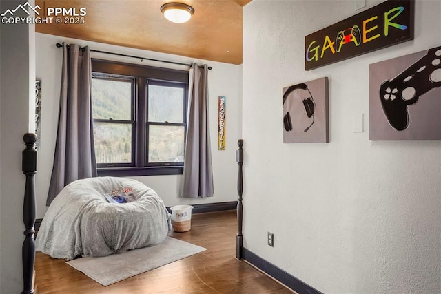 interior space featuring a textured wall, baseboards, and wood finished floors