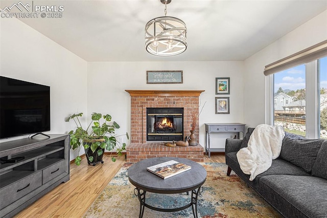 living area featuring baseboards, an inviting chandelier, wood finished floors, and a fireplace