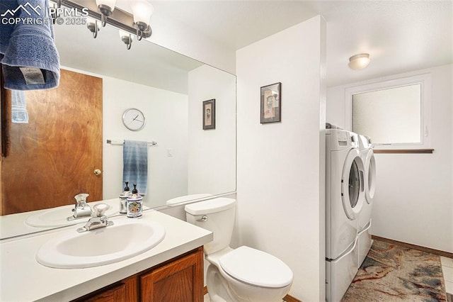 bathroom with toilet, washing machine and clothes dryer, baseboards, and vanity