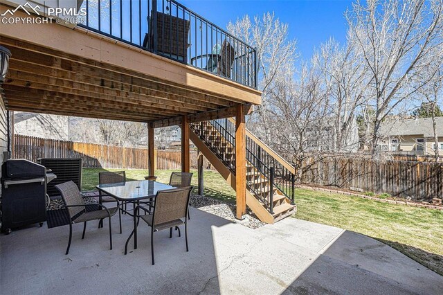 view of patio / terrace with grilling area, outdoor dining space, a fenced backyard, and stairs