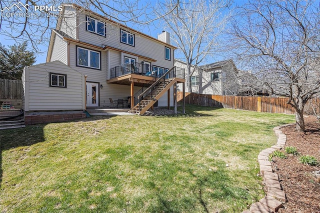 back of house featuring a wooden deck, fence private yard, a lawn, stairs, and a chimney