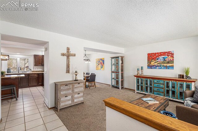 living area featuring light carpet, a textured ceiling, and light tile patterned flooring
