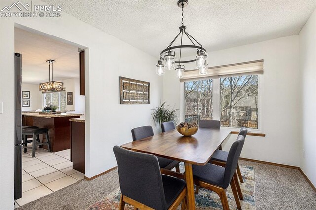 dining space featuring baseboards, light colored carpet, an inviting chandelier, and a textured ceiling