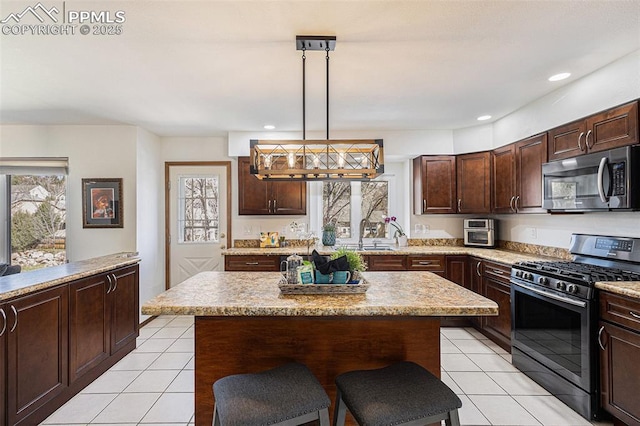 kitchen featuring pendant lighting, dark brown cabinetry, a kitchen breakfast bar, appliances with stainless steel finishes, and light tile patterned flooring