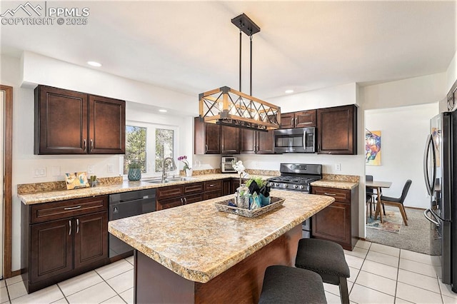 kitchen with a breakfast bar, dark brown cabinets, stainless steel appliances, a sink, and hanging light fixtures