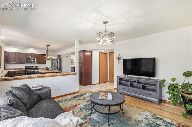 living area with a chandelier, light wood-style floors, and baseboards