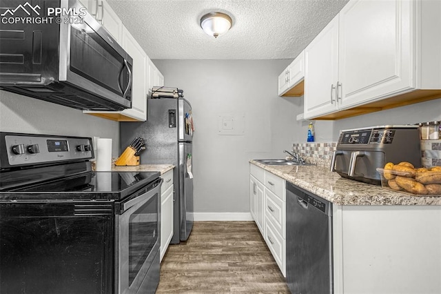 5030 El Camino Dr Unit 1, Colorado Springs, CO 80918 - kitchen featuring white cabinets, appliances with stainless steel finishes, a sink, a textured ceiling, and wood finished floors