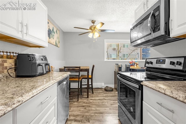 5030 El Camino Dr Unit 1, Colorado Springs, CO 80918 - kitchen with ceiling fan, a textured ceiling, white cabinets, light wood-style flooring, and stainless steel appliances