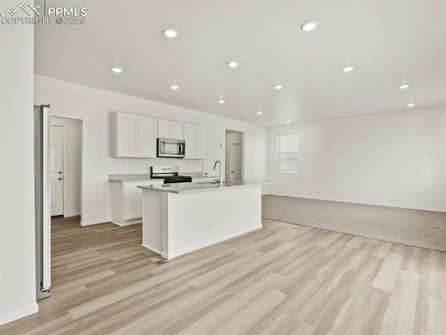 kitchen featuring an island with sink, white cabinetry, light wood-style floors, and appliances with stainless steel finishes