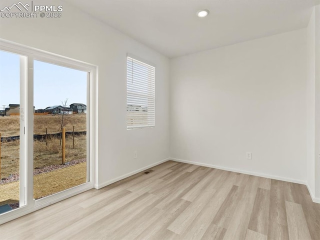 unfurnished room with baseboards, light wood finished floors, and recessed lighting