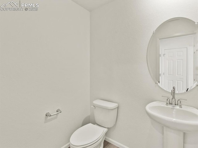 bathroom with baseboards, a sink, and toilet