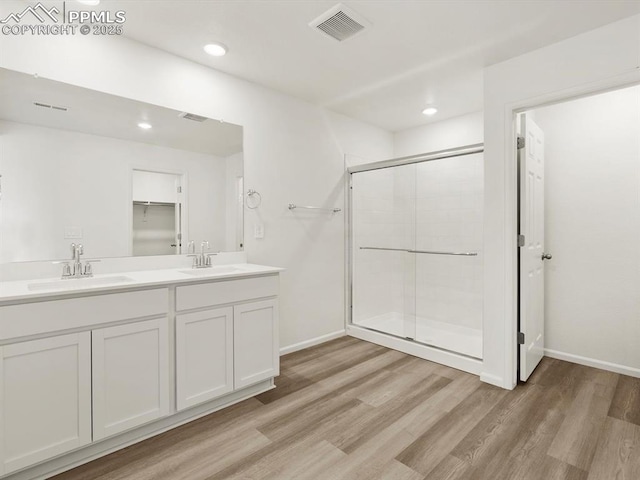 bathroom with wood finished floors, visible vents, a stall shower, and a sink