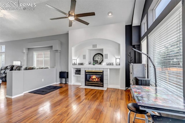 4626 Hotspur Dr, Colorado Springs, CO 80922 - living area with wood-type flooring, baseboards, a tiled fireplace, a textured ceiling, and ceiling fan