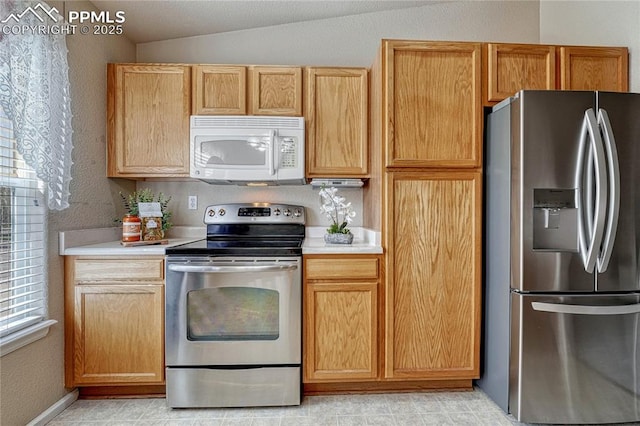 5542 Sunshade Pt, Colorado Springs, CO 80923 - kitchen featuring appliances with stainless steel finishes, a textured wall, light countertops, and vaulted ceiling