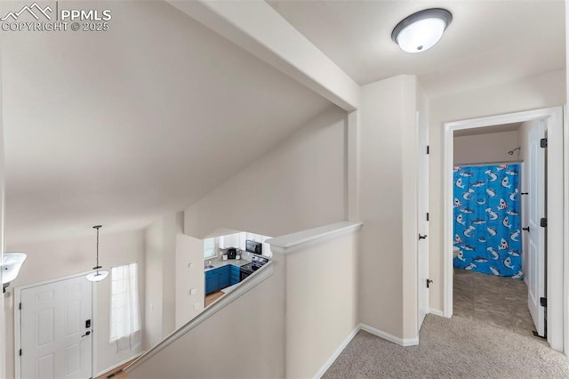 hallway with baseboards, carpet flooring, and an upstairs landing