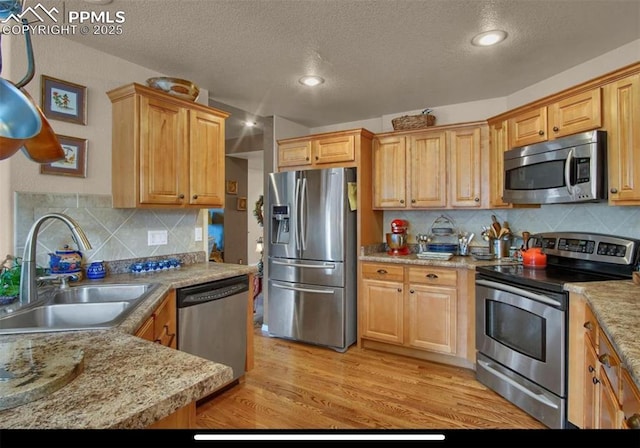 8723 Stony Creek Dr, Colorado Springs, CO 80924 - kitchen featuring stainless steel appliances, a sink, a textured ceiling, tasteful backsplash, and light wood finished floors