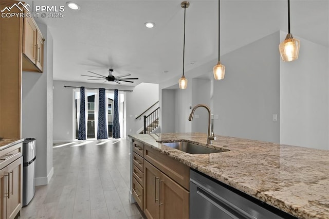 kitchen featuring light stone countertops, ceiling fan, stainless steel dishwasher, pendant lighting, and a sink