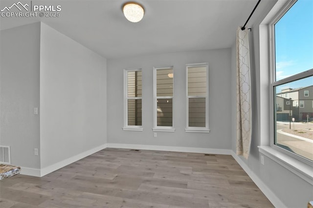spare room with visible vents, baseboards, and wood finished floors