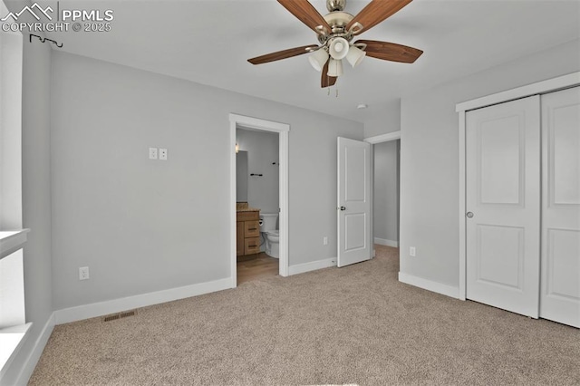unfurnished bedroom with a closet, baseboards, ensuite bath, carpet floors, and visible vents