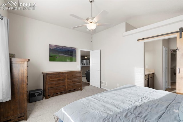955 S Los Charros Dr, Pueblo West, CO 81007 - bedroom featuring light carpet, connected bathroom, a barn door, visible vents, and ceiling fan