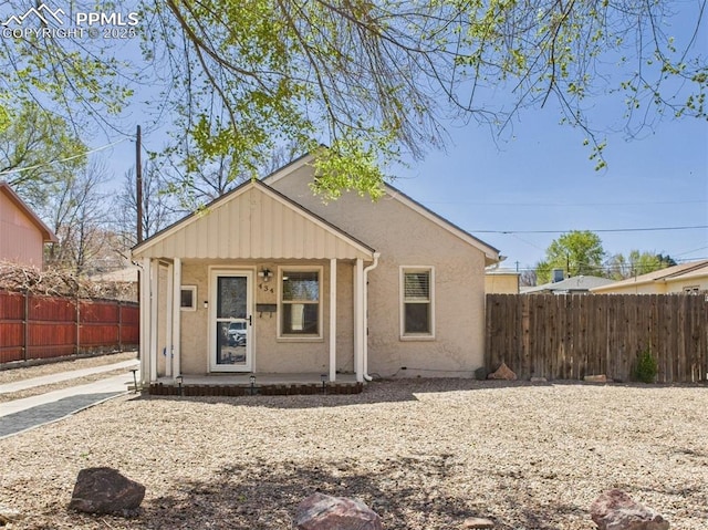 bungalow-style home featuring stucco siding and fence