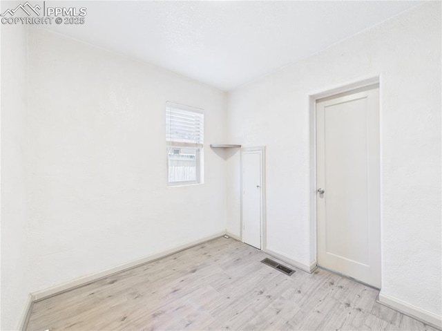 empty room with visible vents, baseboards, and wood finished floors