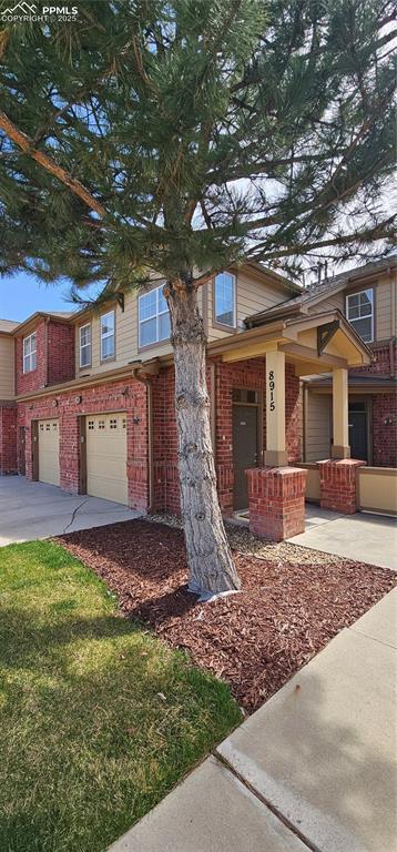 view of front facade with a garage, brick siding, and driveway