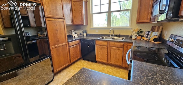 kitchen with brown cabinets, a sink, black appliances, and dark countertops