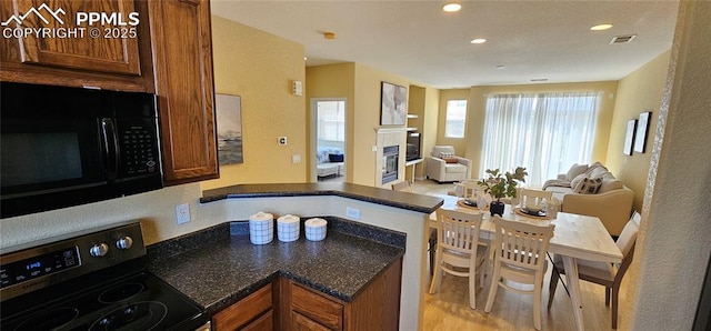 kitchen featuring black microwave, brown cabinetry, stainless steel range with electric stovetop, visible vents, and open floor plan